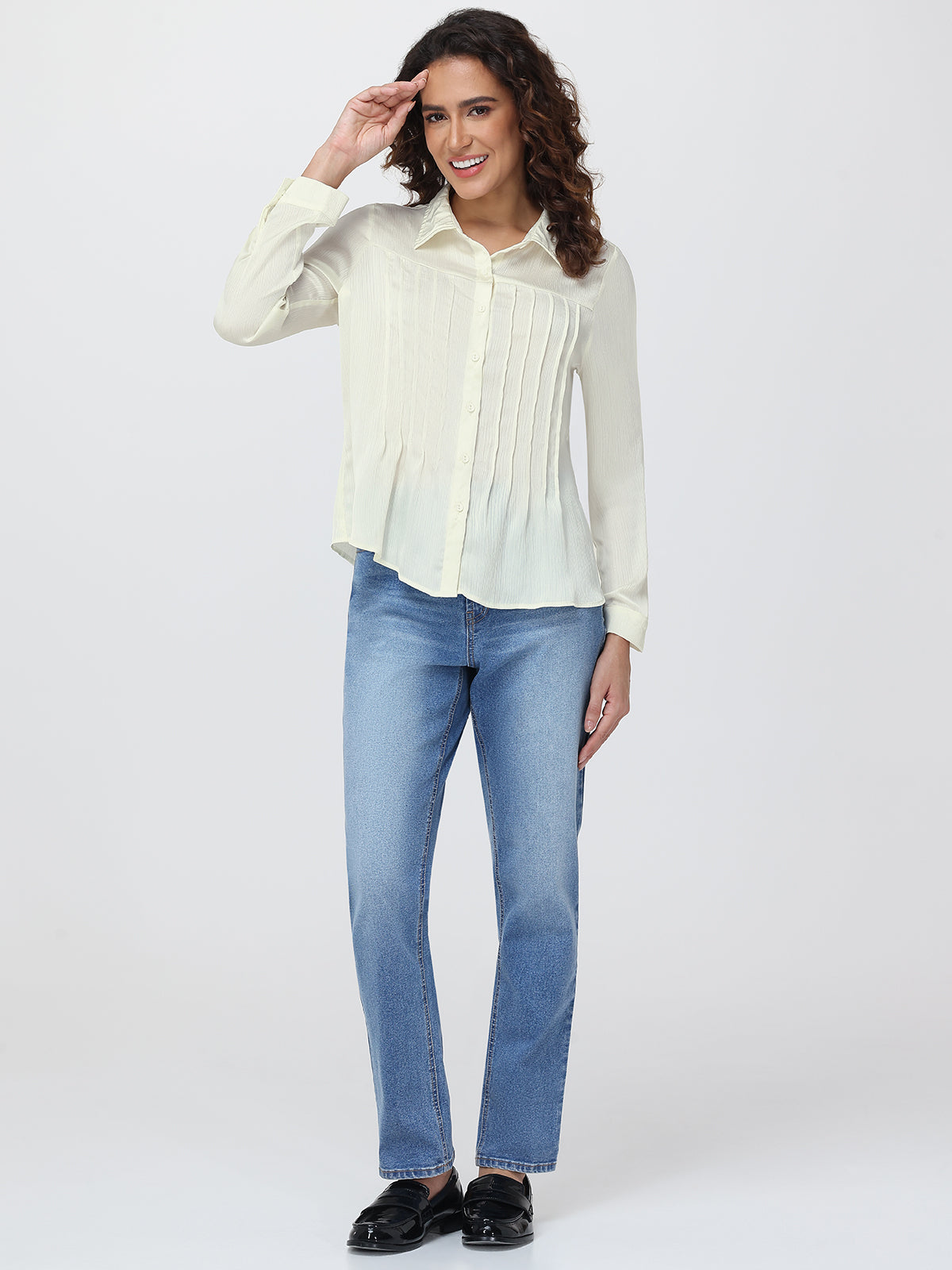 Woman wearing a light-colored blouse and blue jeans on a white background