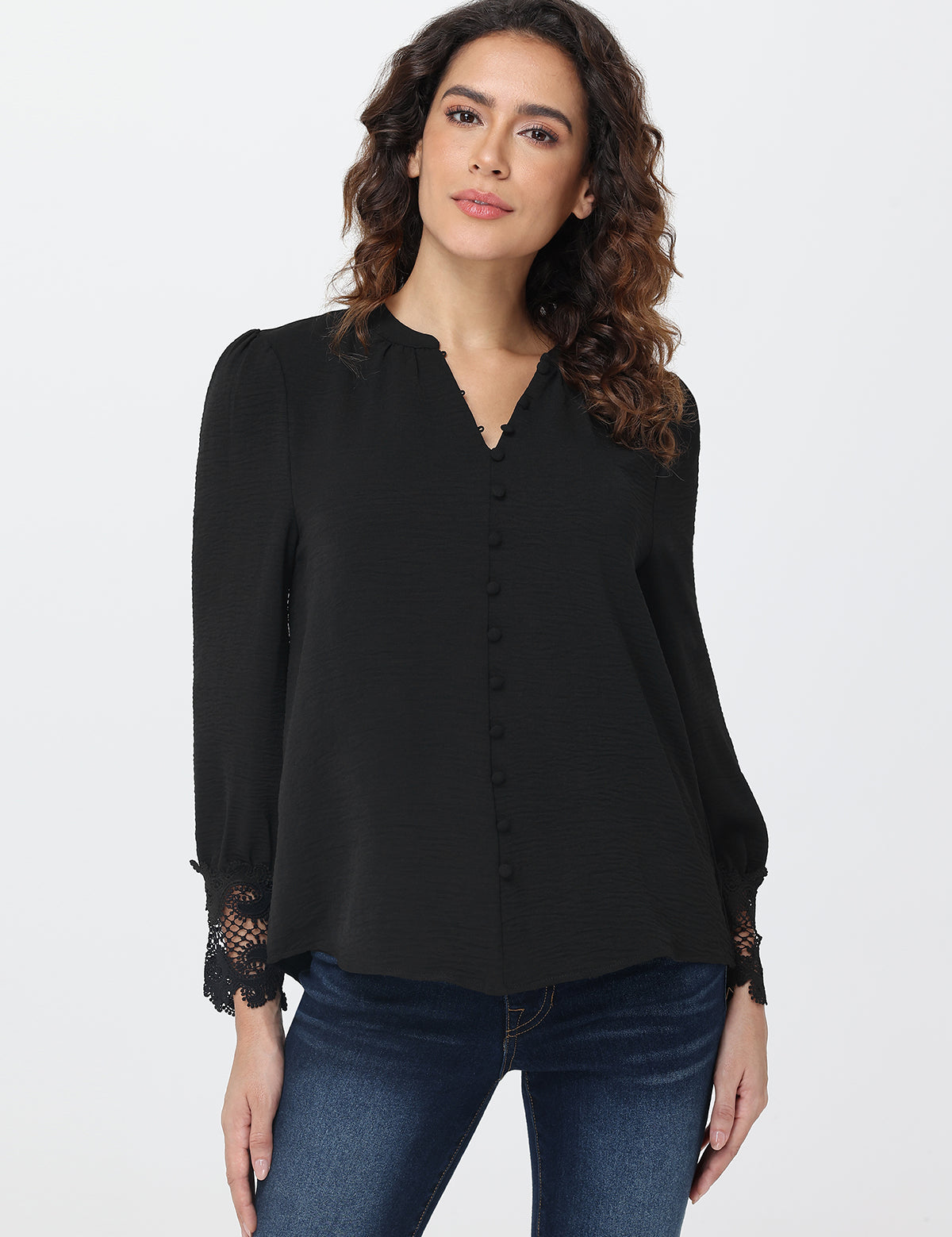 Woman wearing a black blouse with lace cuffs on a white background