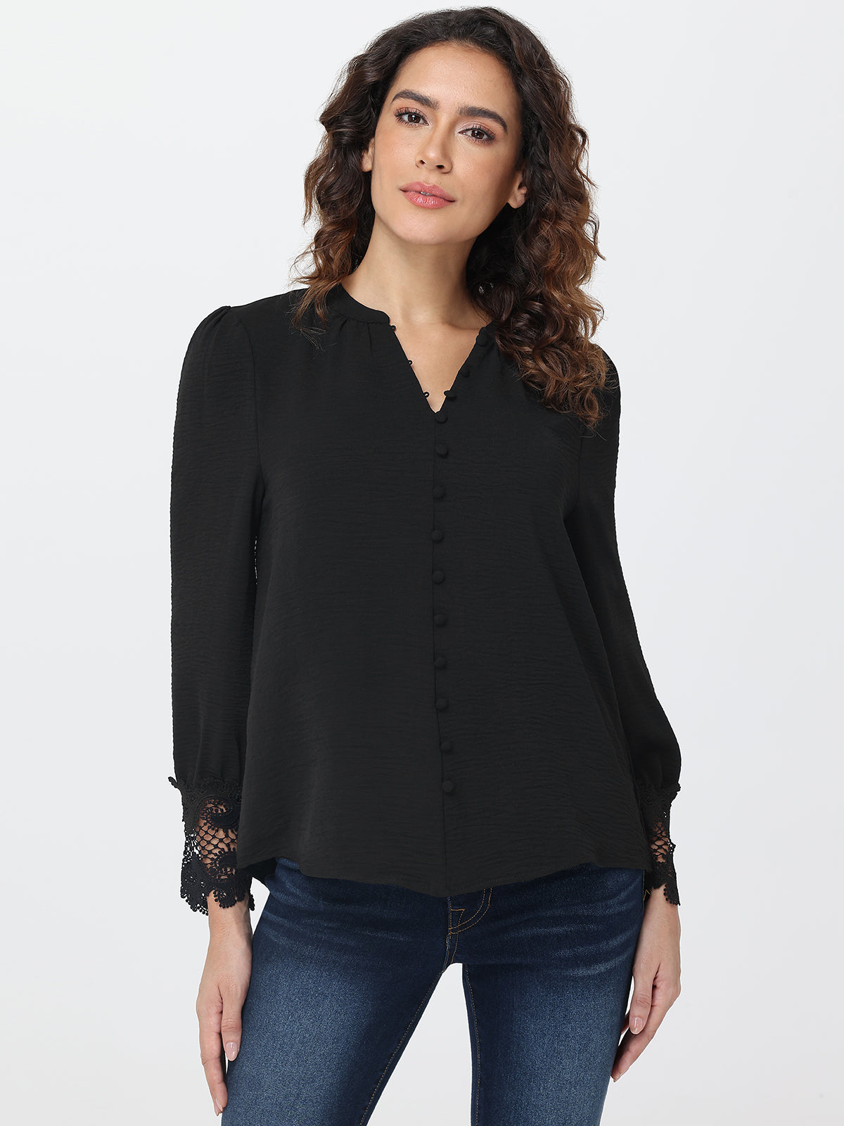 Woman wearing a black blouse with lace cuffs on a white background