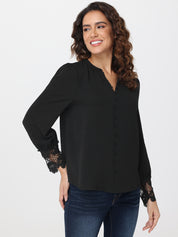 Woman wearing a black blouse with lace cuffs on a white background