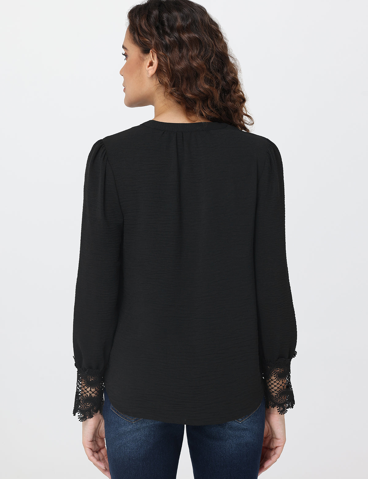 Woman wearing a black blouse with lace cuffs on a white background