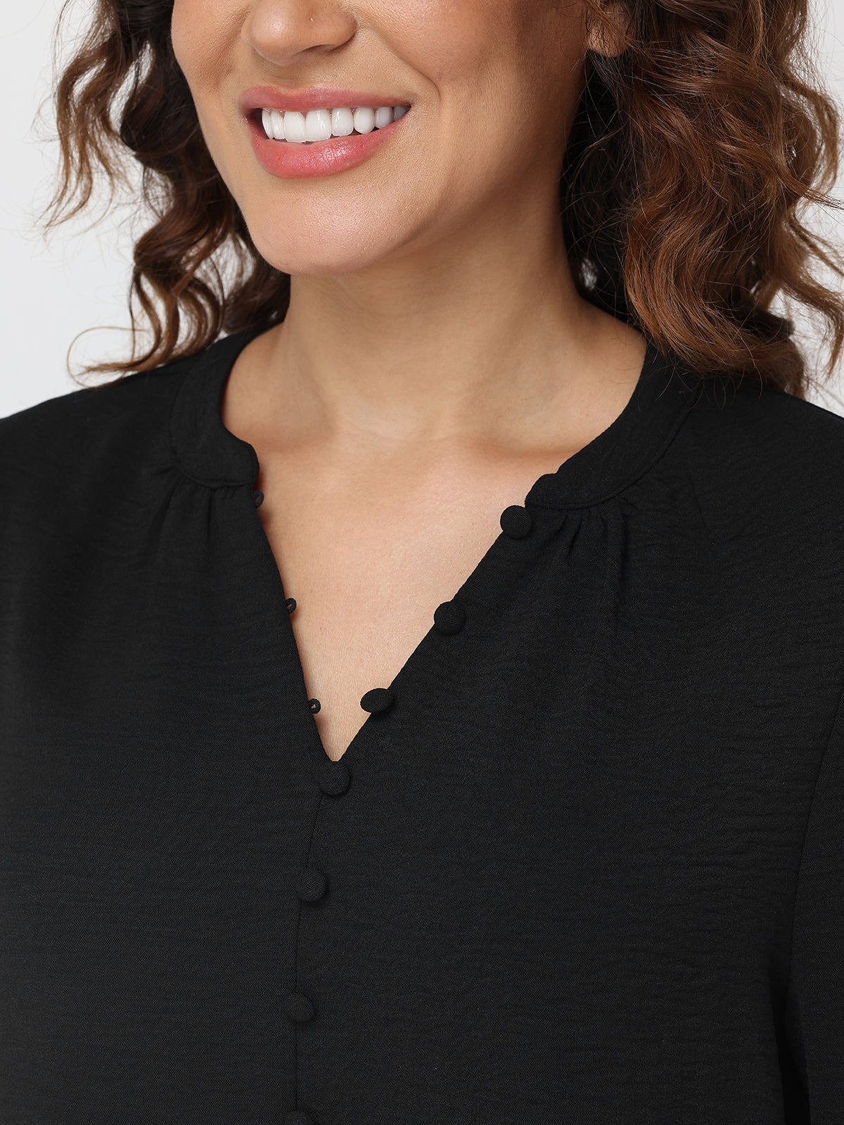 Close-up of a person wearing a black blouse with a plain background