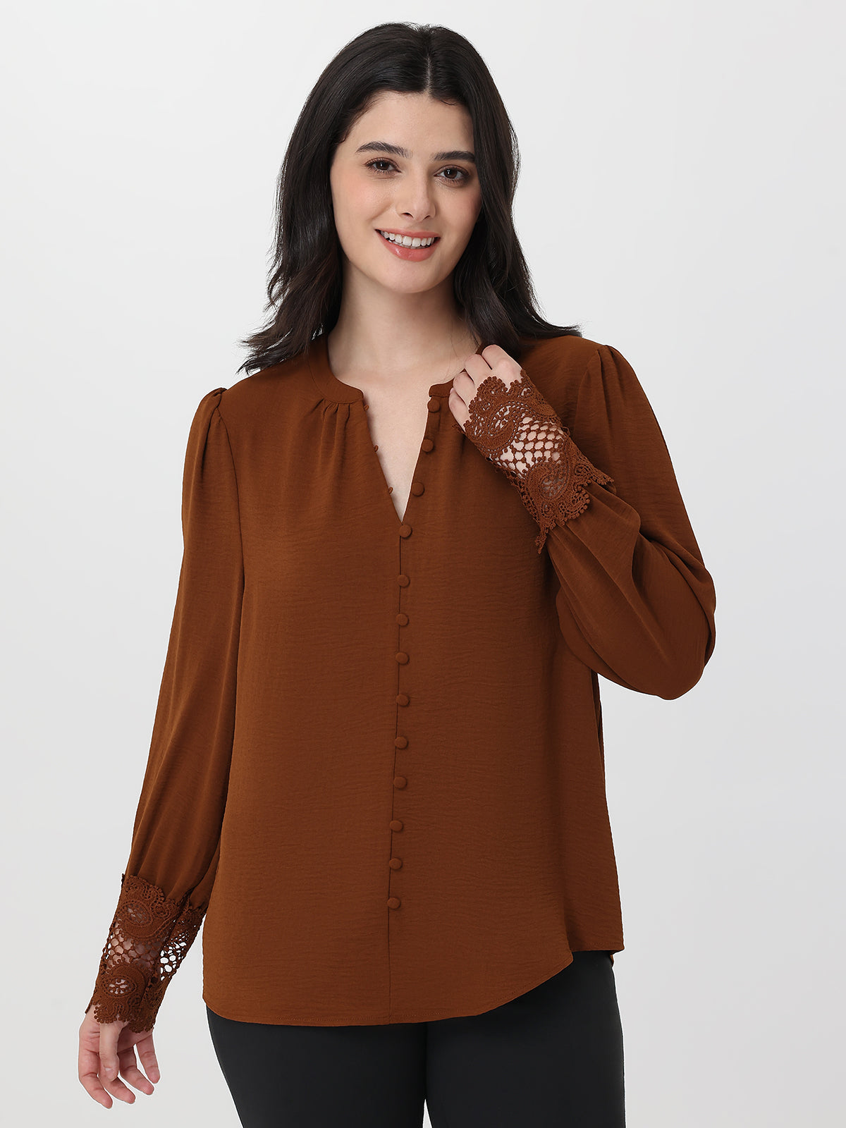 Woman wearing a brown blouse with lace sleeves on a white background