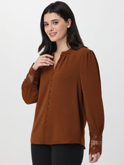 Woman wearing a brown blouse with lace cuffs on a white background
