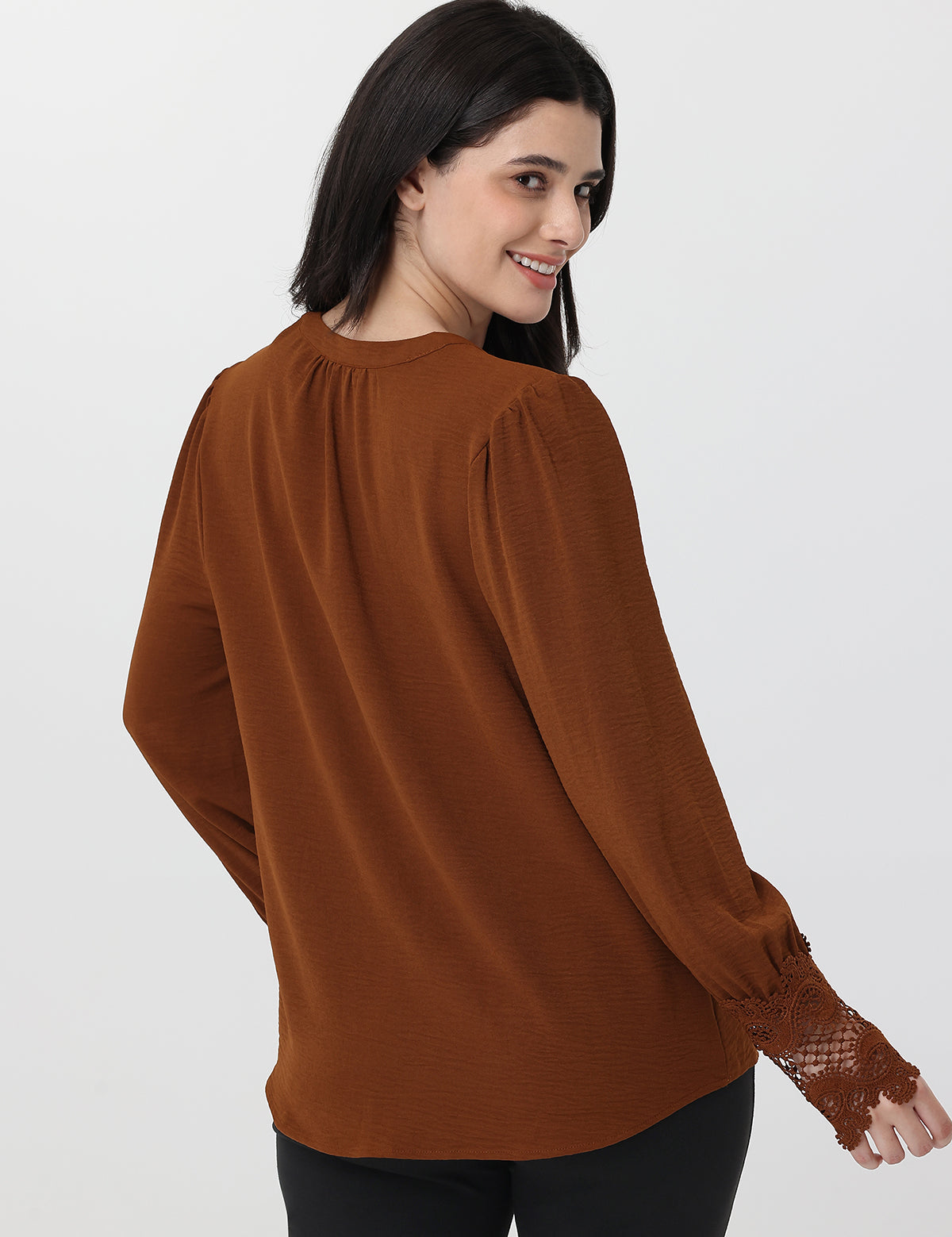 Woman wearing a brown blouse with lace cuffs on a white background