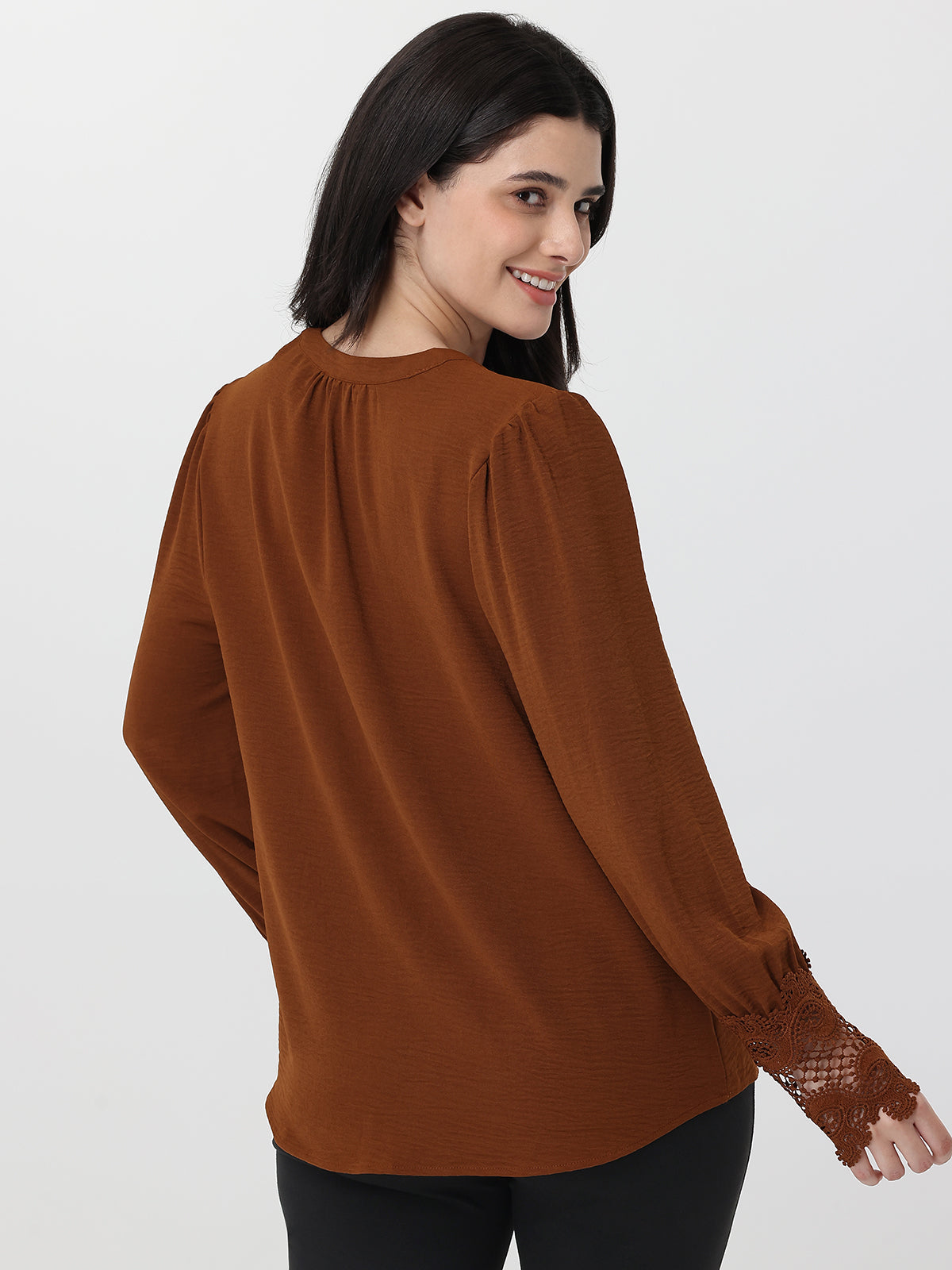 Woman wearing a brown blouse with lace cuffs on a white background