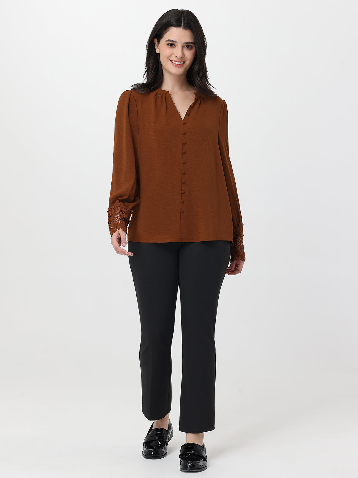 Woman wearing a brown blouse and black pants on a white background