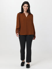 Woman wearing a brown blouse and black pants on a white background
