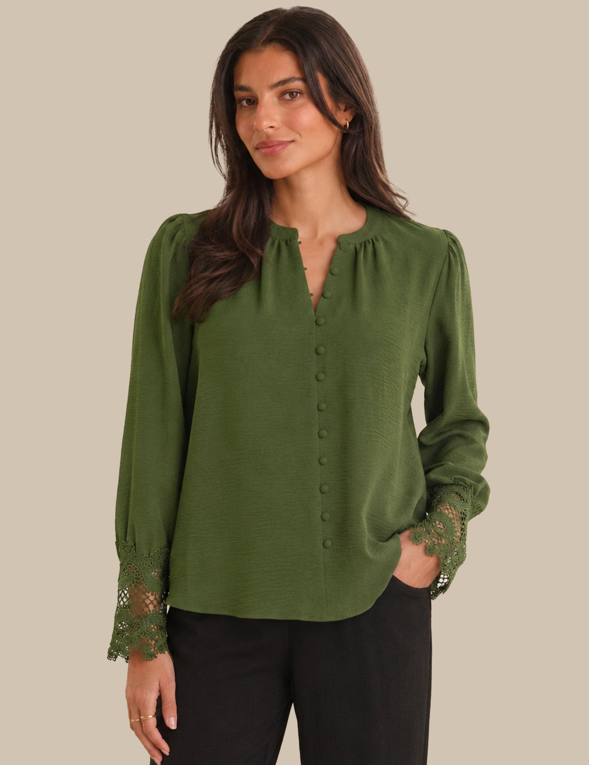 Woman wearing a green blouse with lace details on a beige background