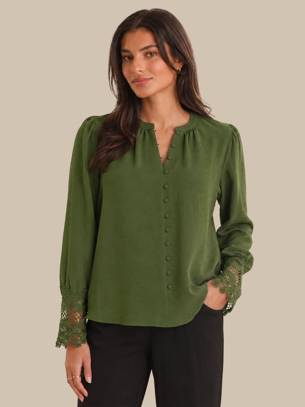 Woman wearing a green blouse with lace details on a beige background