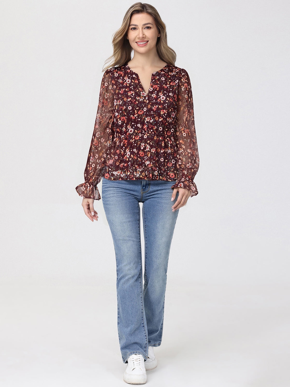 Woman wearing a floral blouse and blue jeans on a white background