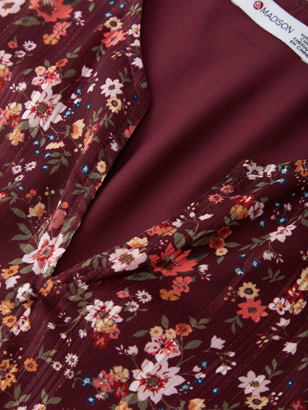 Close-up of floral fabric with a visible brand label on a dark red background