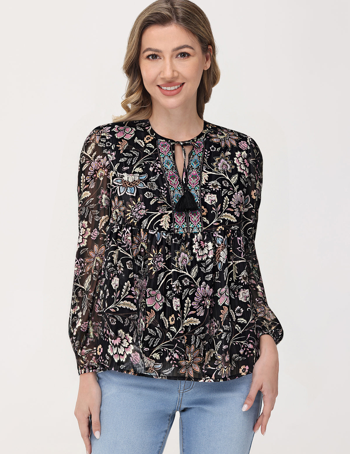Woman wearing a black floral blouse with light blue jeans on a white background