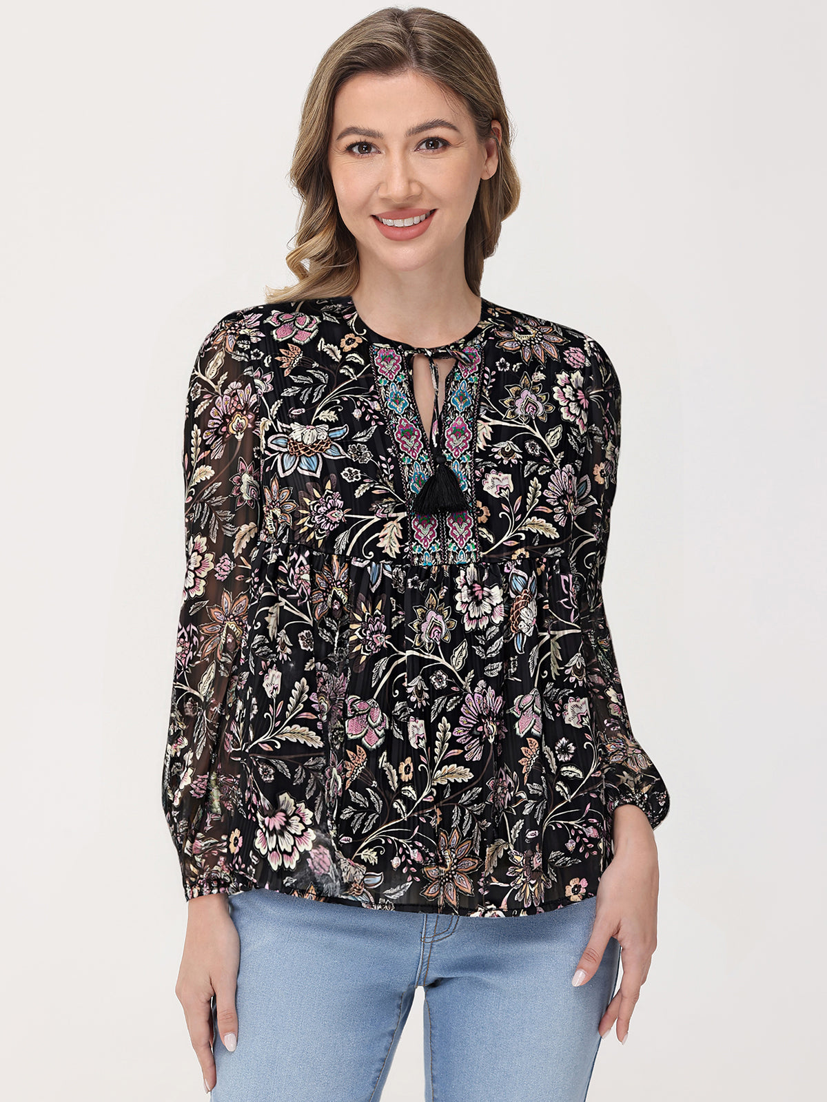 Woman wearing a black floral blouse with light blue jeans on a white background