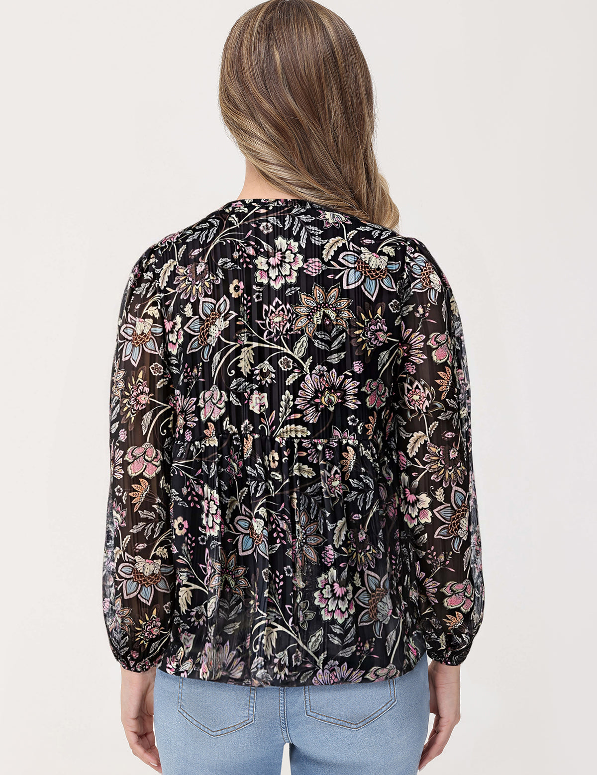 Woman wearing a black floral blouse with a plain background
