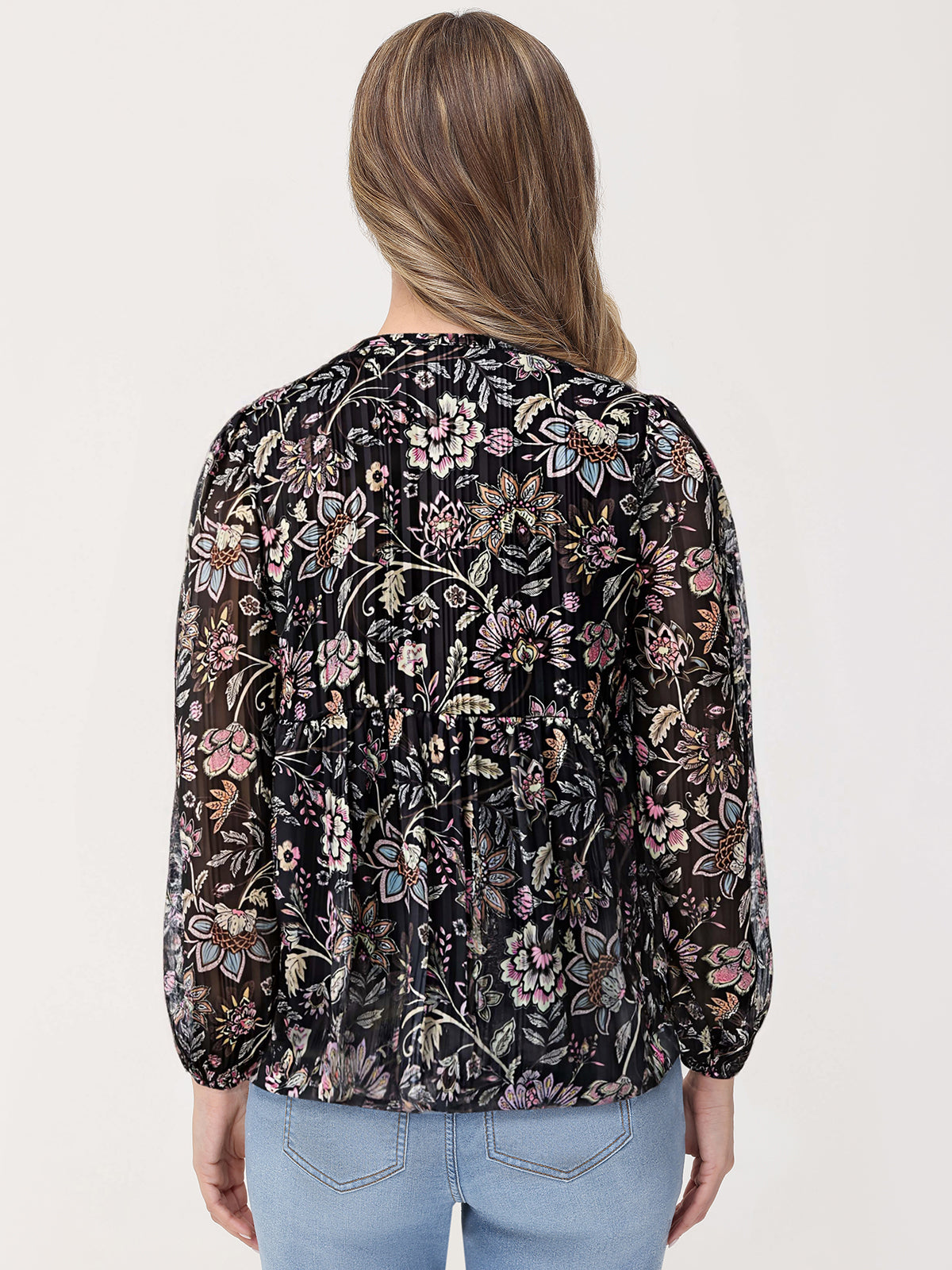 Woman wearing a black floral blouse with a plain background