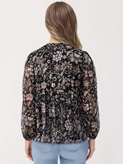 Woman wearing a black floral blouse with a plain background