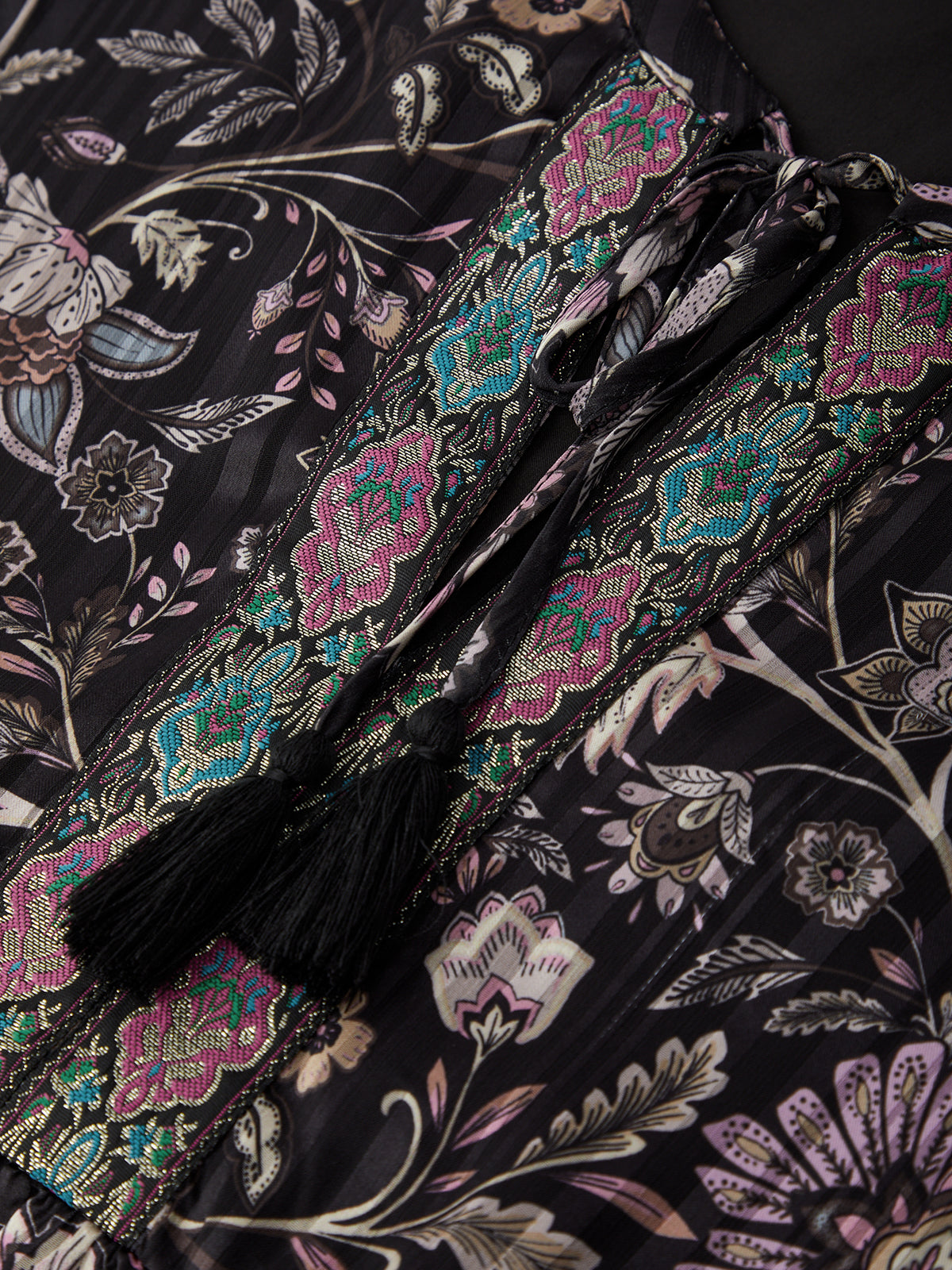 Close-up of a floral-patterned fabric with tassels on a dark background