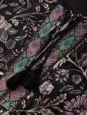 Close-up of a floral-patterned fabric with tassels on a dark background