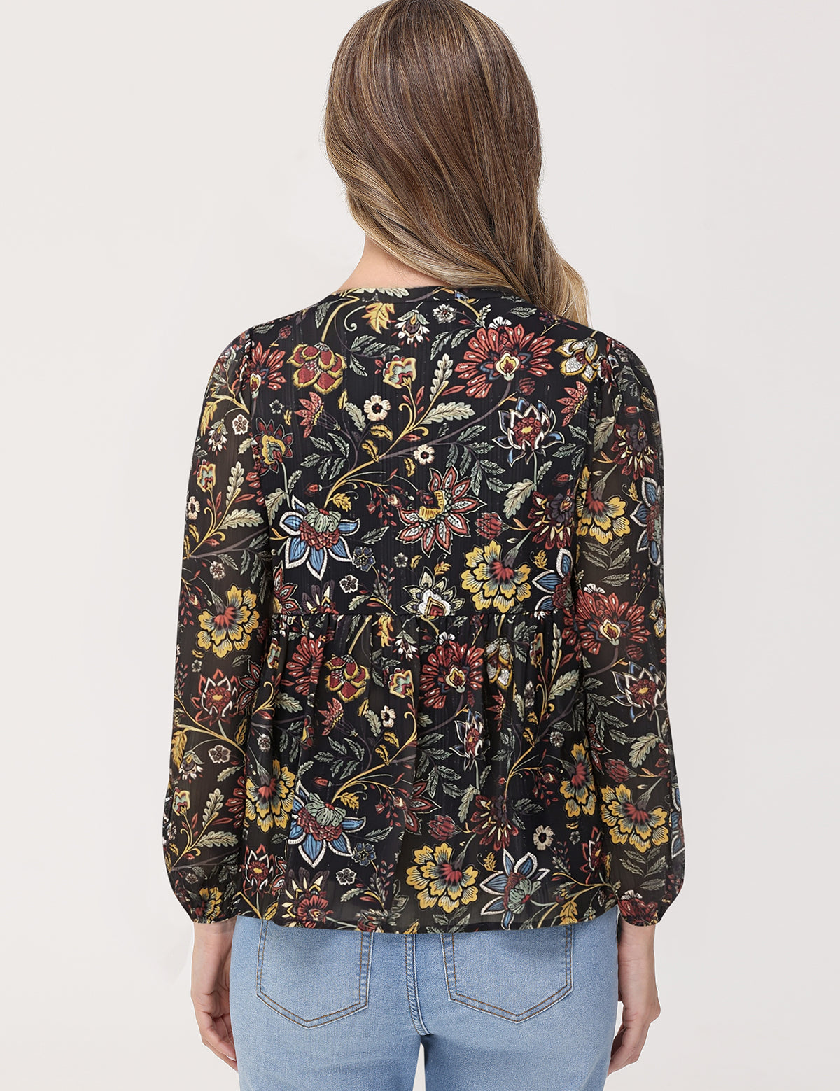 Woman wearing a floral patterned blouse with long sleeves on a plain background