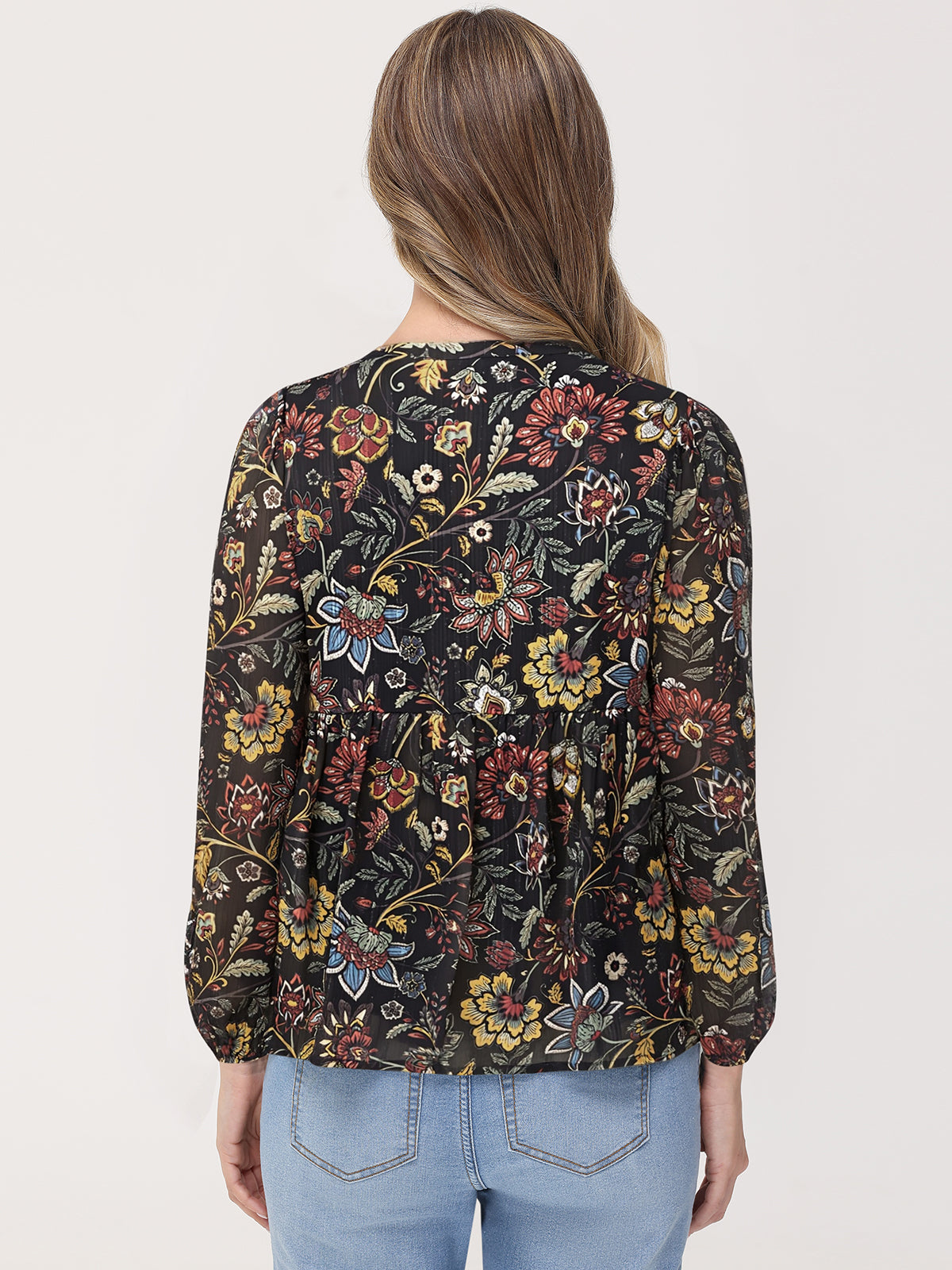 Woman wearing a floral patterned blouse with long sleeves on a plain background