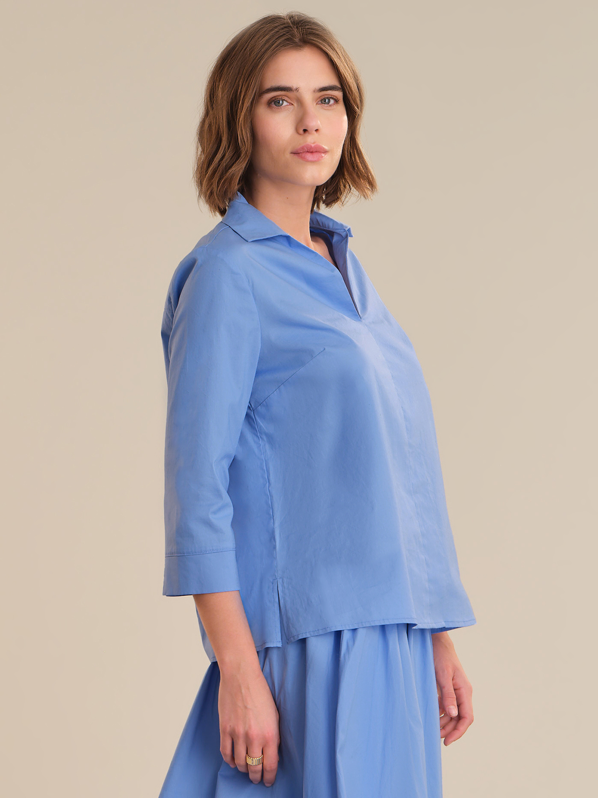 Woman wearing a blue outfit against a beige background