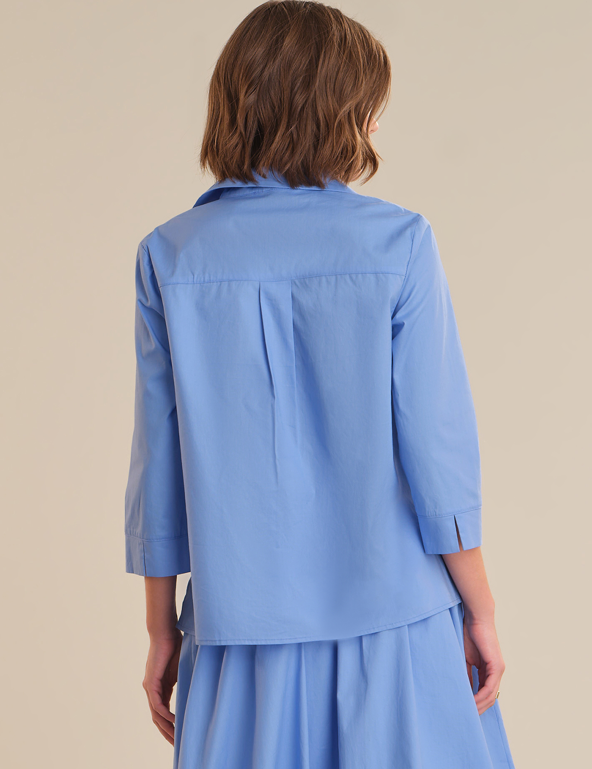 Woman wearing a blue outfit against a beige background