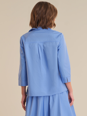 Woman wearing a blue outfit against a beige background