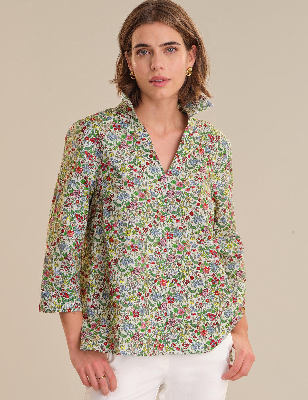 Woman wearing a floral patterned shirt against a beige background