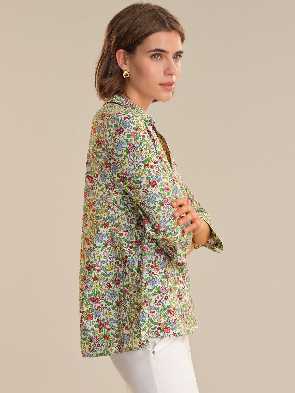 Woman wearing a floral print shirt against a beige background