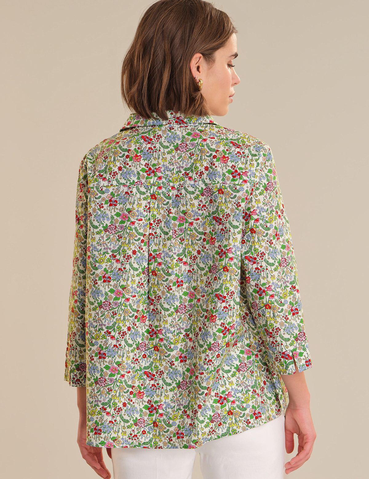 Woman wearing a floral patterned blouse against a beige background