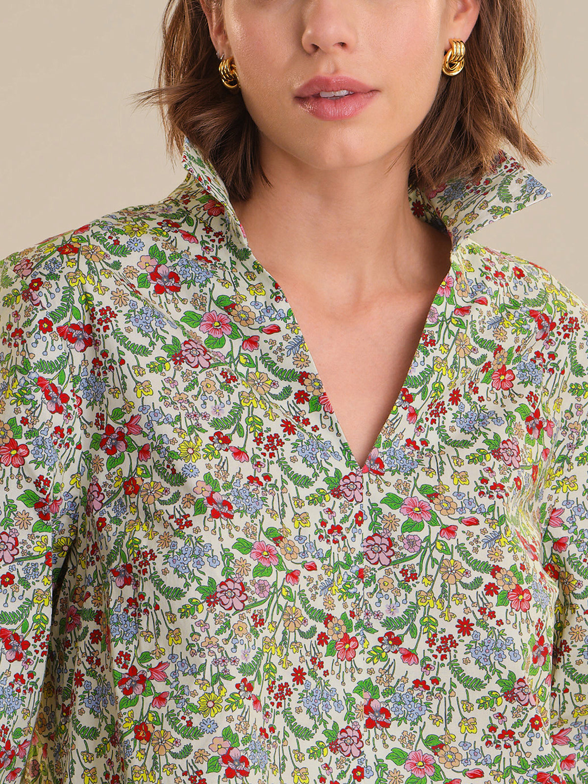 Woman wearing a floral patterned shirt with a neutral background