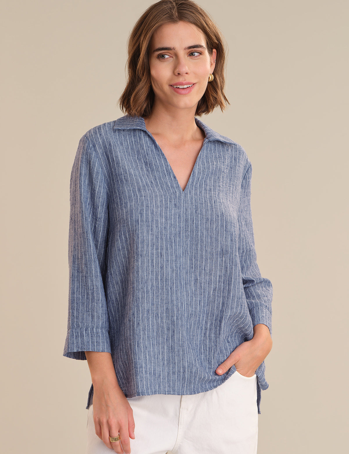 Woman wearing a blue striped shirt against a beige background