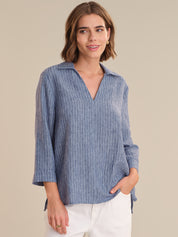 Woman wearing a blue striped shirt against a beige background