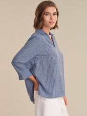 Woman wearing a blue striped shirt against a beige background