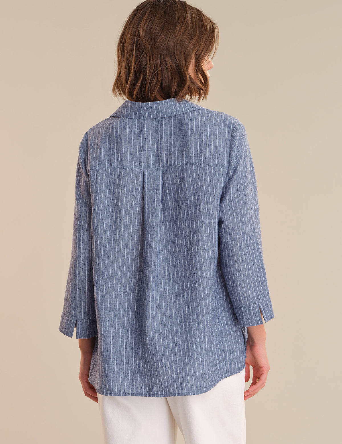 Woman wearing a blue striped shirt against a beige background