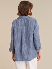 Woman wearing a blue striped shirt against a beige background