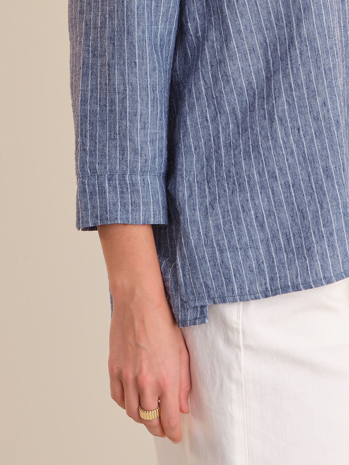 Close-up of a person wearing a blue striped shirt with a beige background
