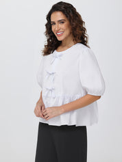 Woman wearing a white blouse with puff sleeves on a plain background