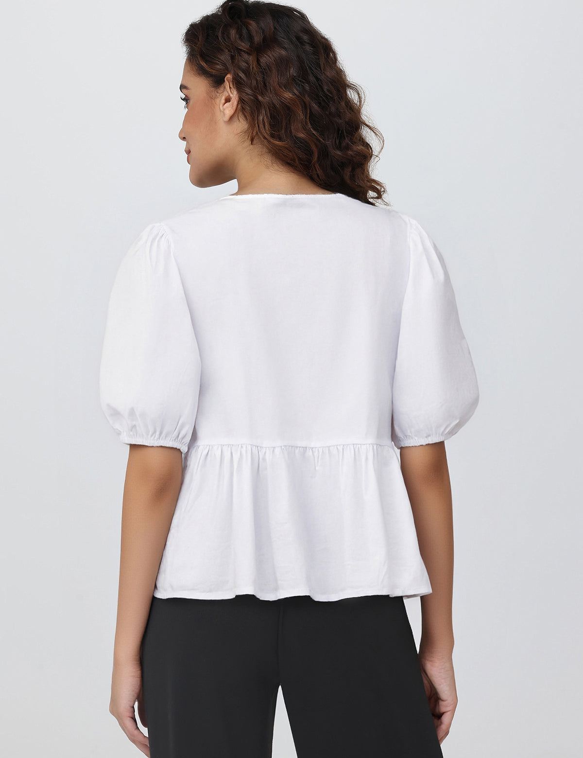 Woman wearing a white blouse with puff sleeves on a plain background