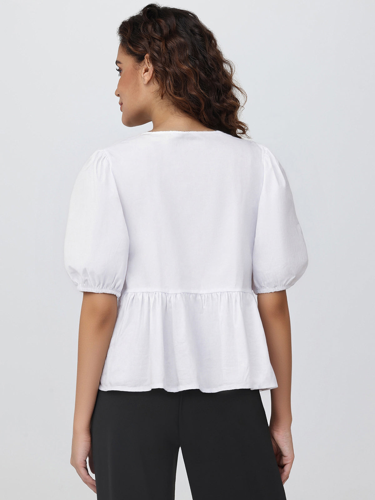 Woman wearing a white blouse with puff sleeves on a plain background