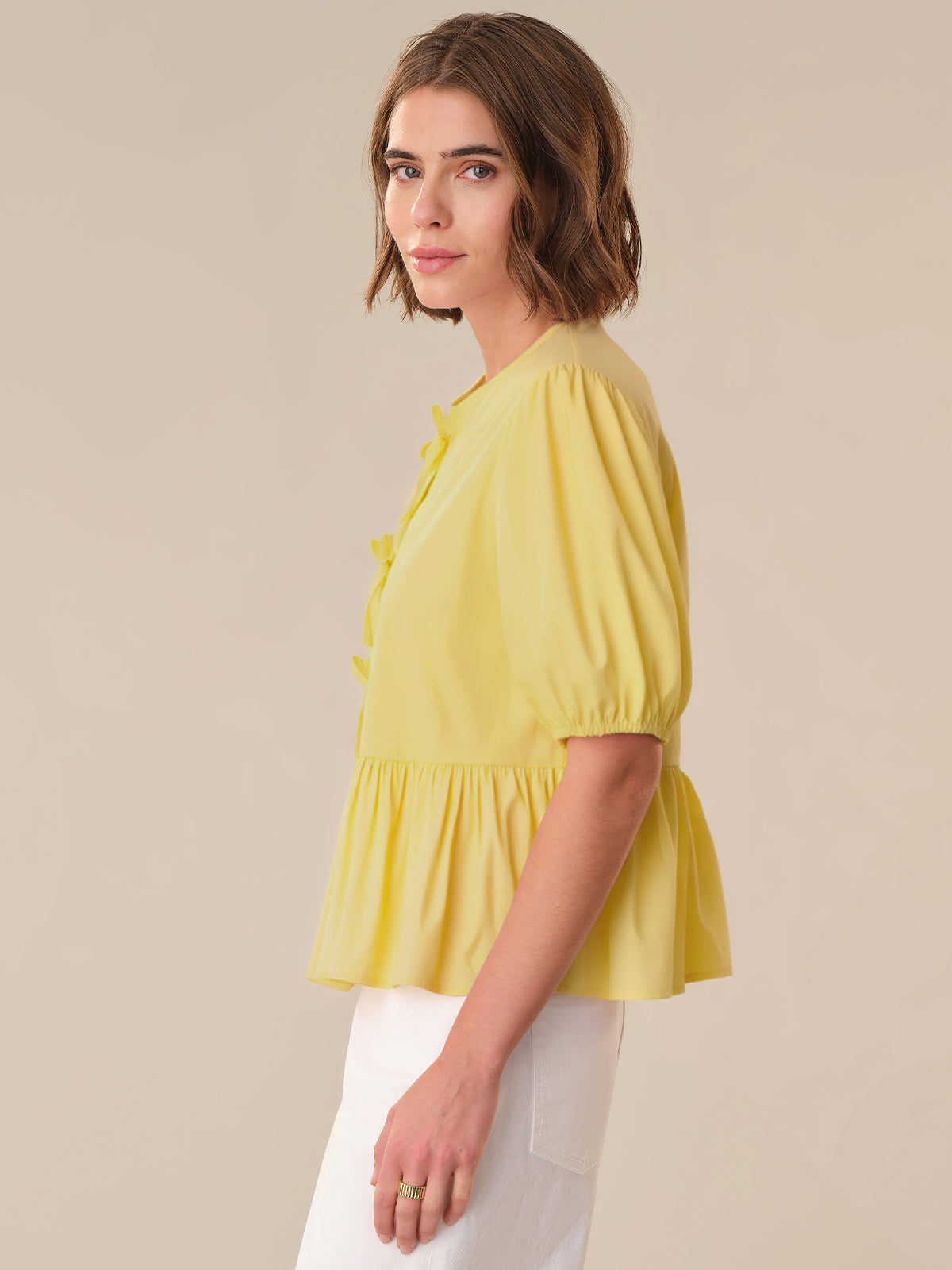 Woman wearing a yellow blouse with a plain background