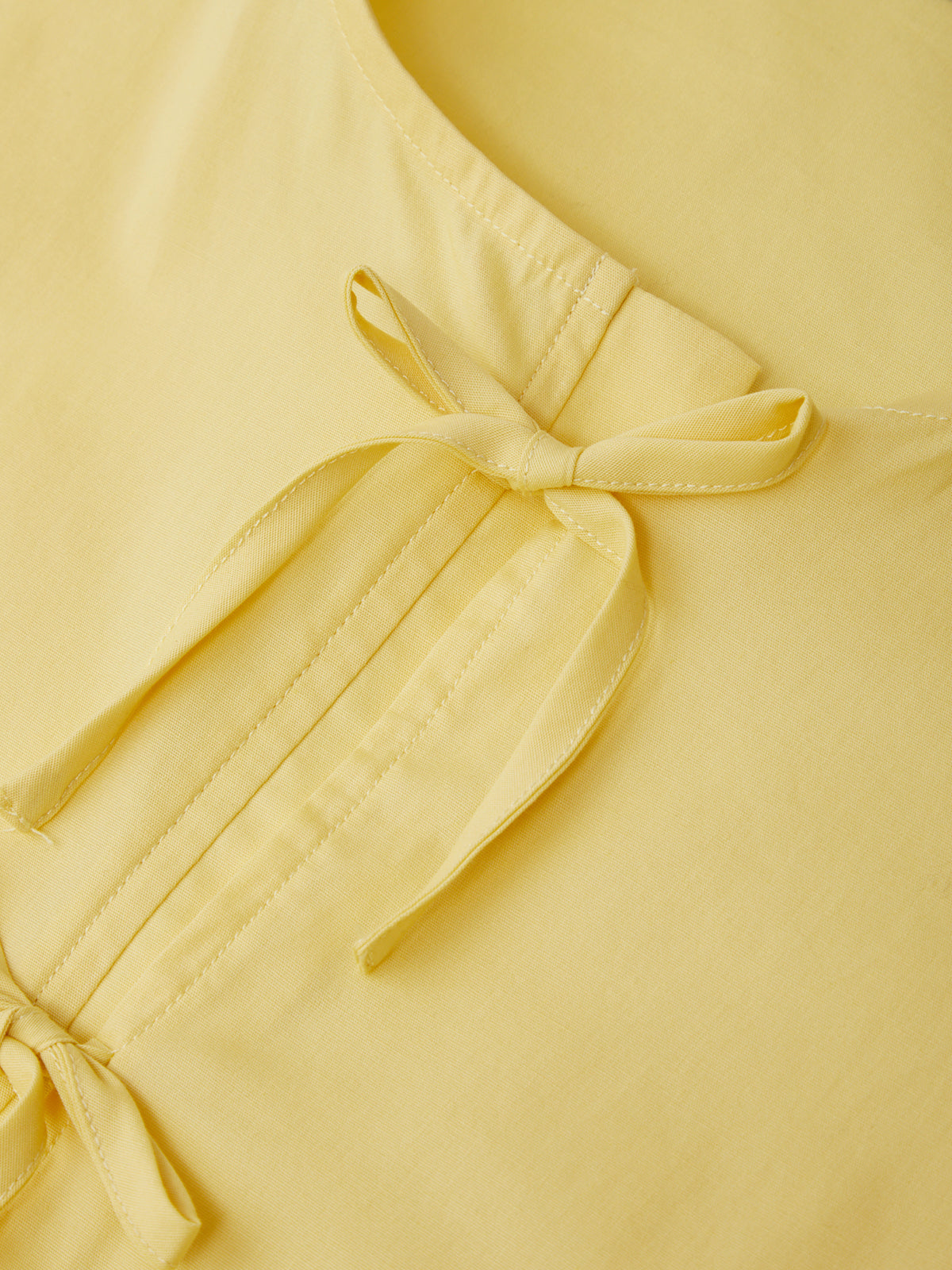 Close-up of a yellow garment with a bow detail