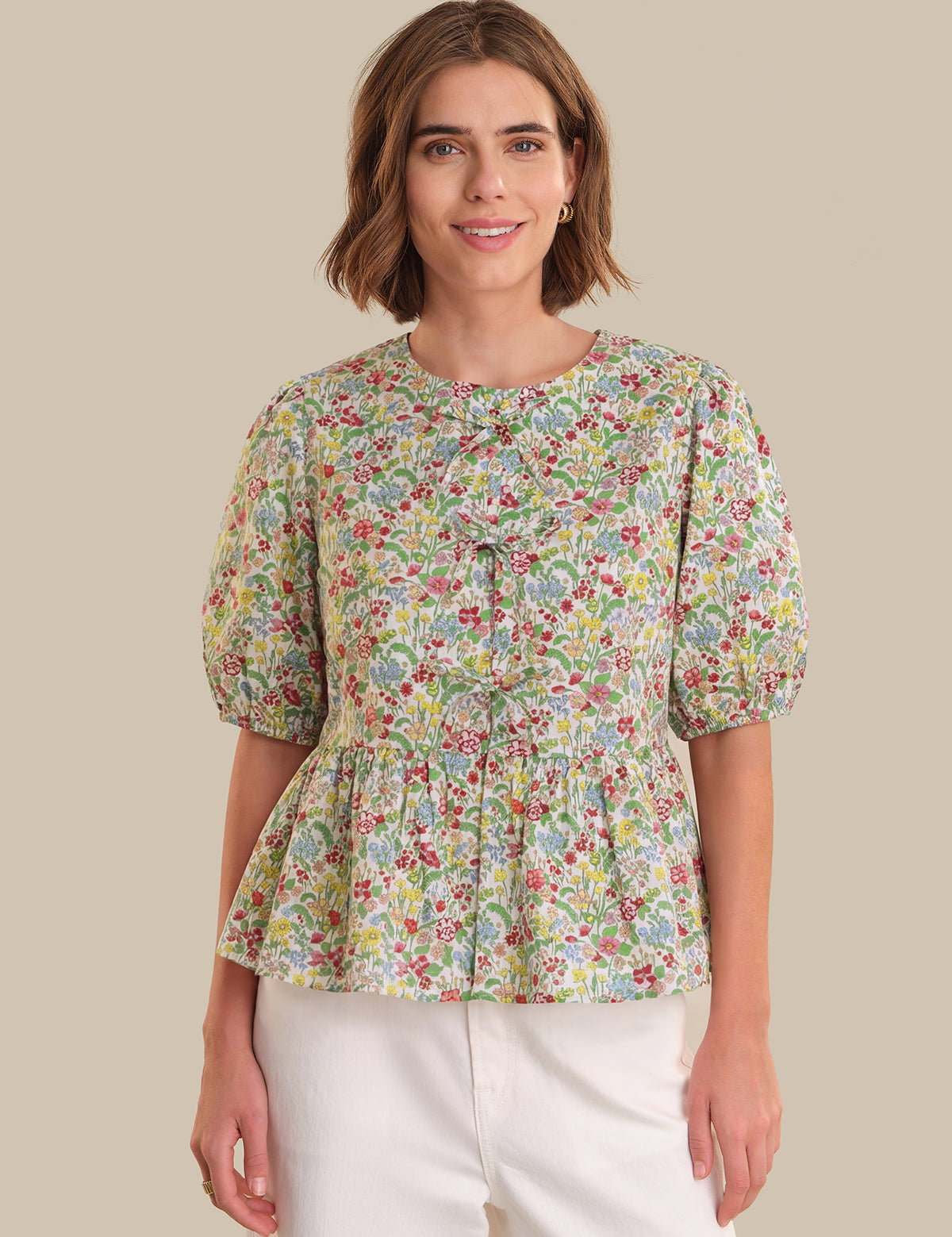 Woman wearing a floral blouse with puff sleeves on a beige background