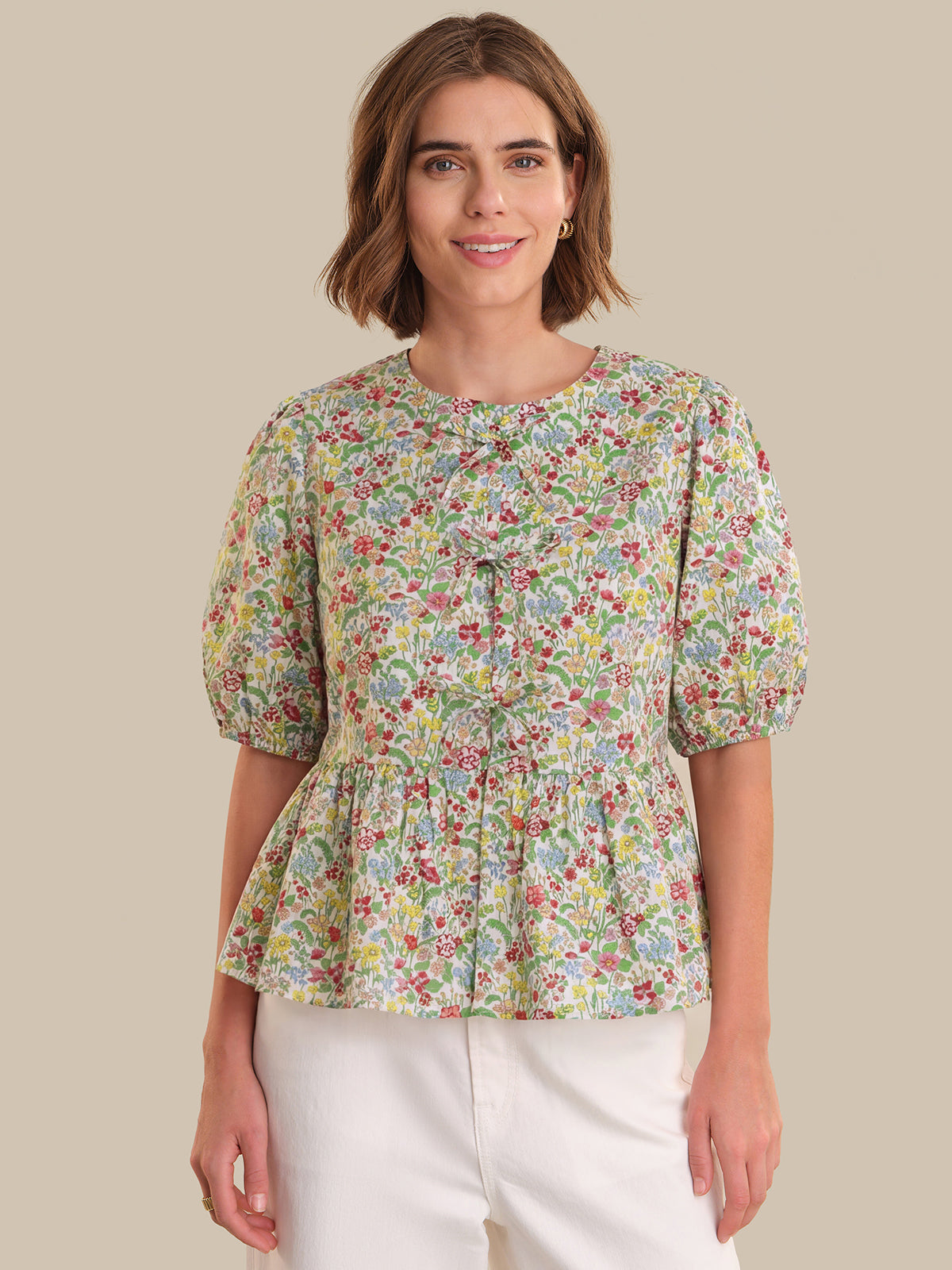 Woman wearing a floral blouse with puff sleeves on a beige background