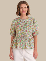 Woman wearing a floral blouse with puff sleeves on a beige background