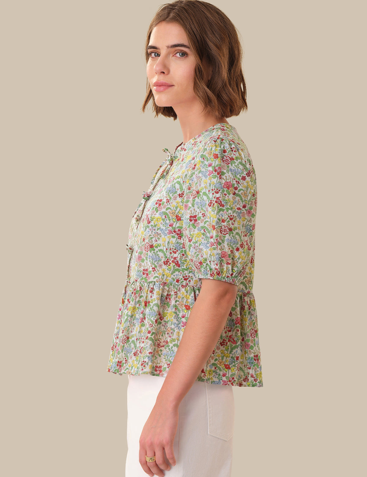 Woman wearing a floral blouse against a beige background