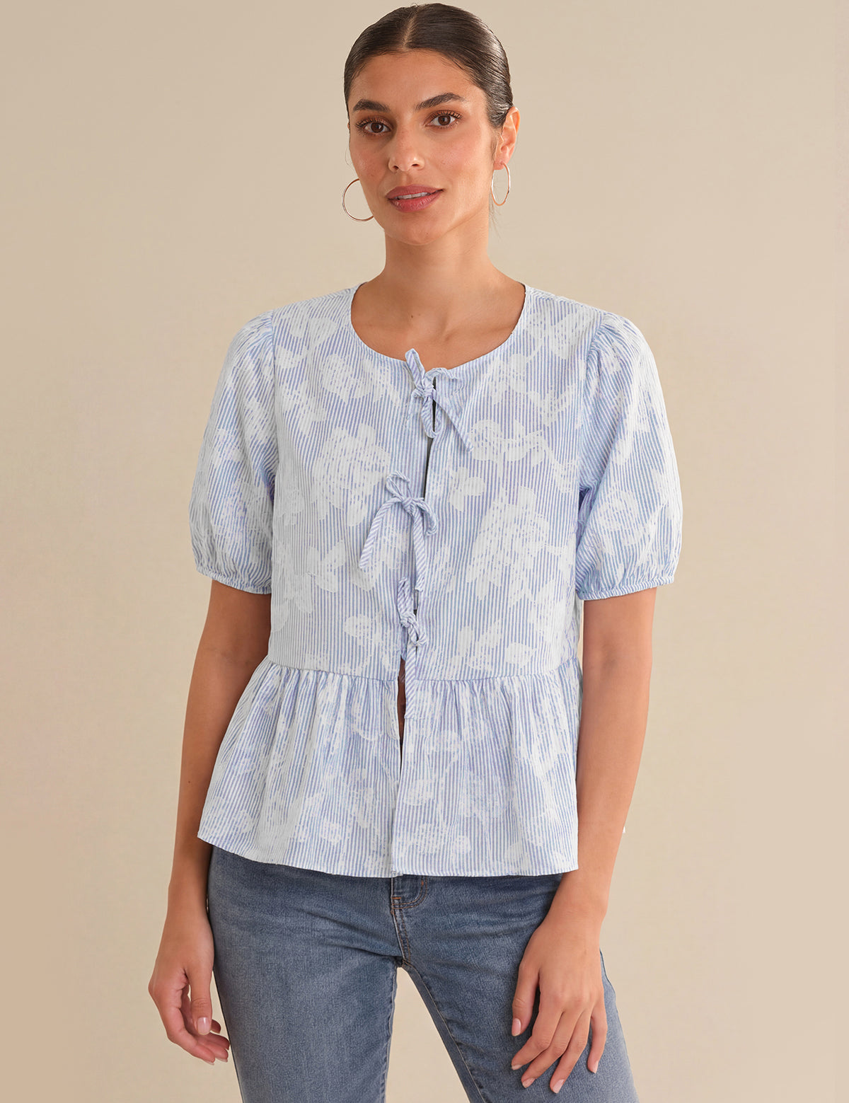 Woman wearing a light blue floral blouse with a beige background