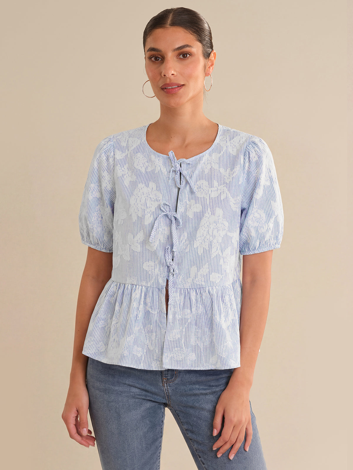 Woman wearing a light blue floral blouse with a beige background