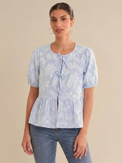 Woman wearing a light blue floral blouse with a beige background